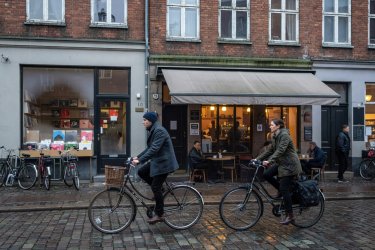 Vesterbro street scene with cyclists passing independent record store and coffee bar