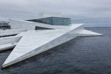 The angled marble roof slopes of Oslo Opera House descending into the fjord waters